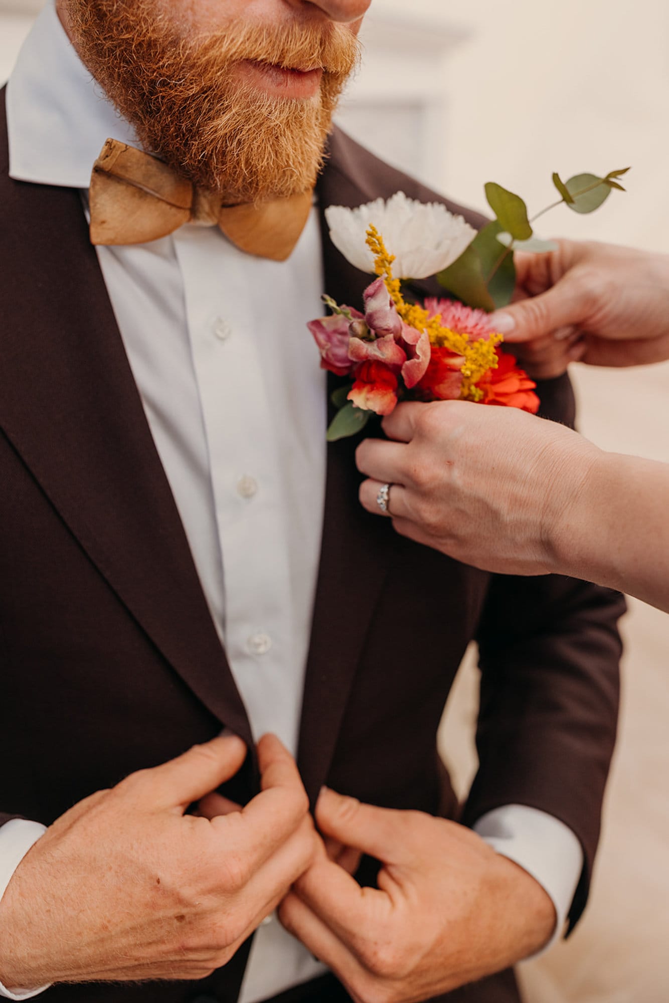 The bride pins flowers to the groom.