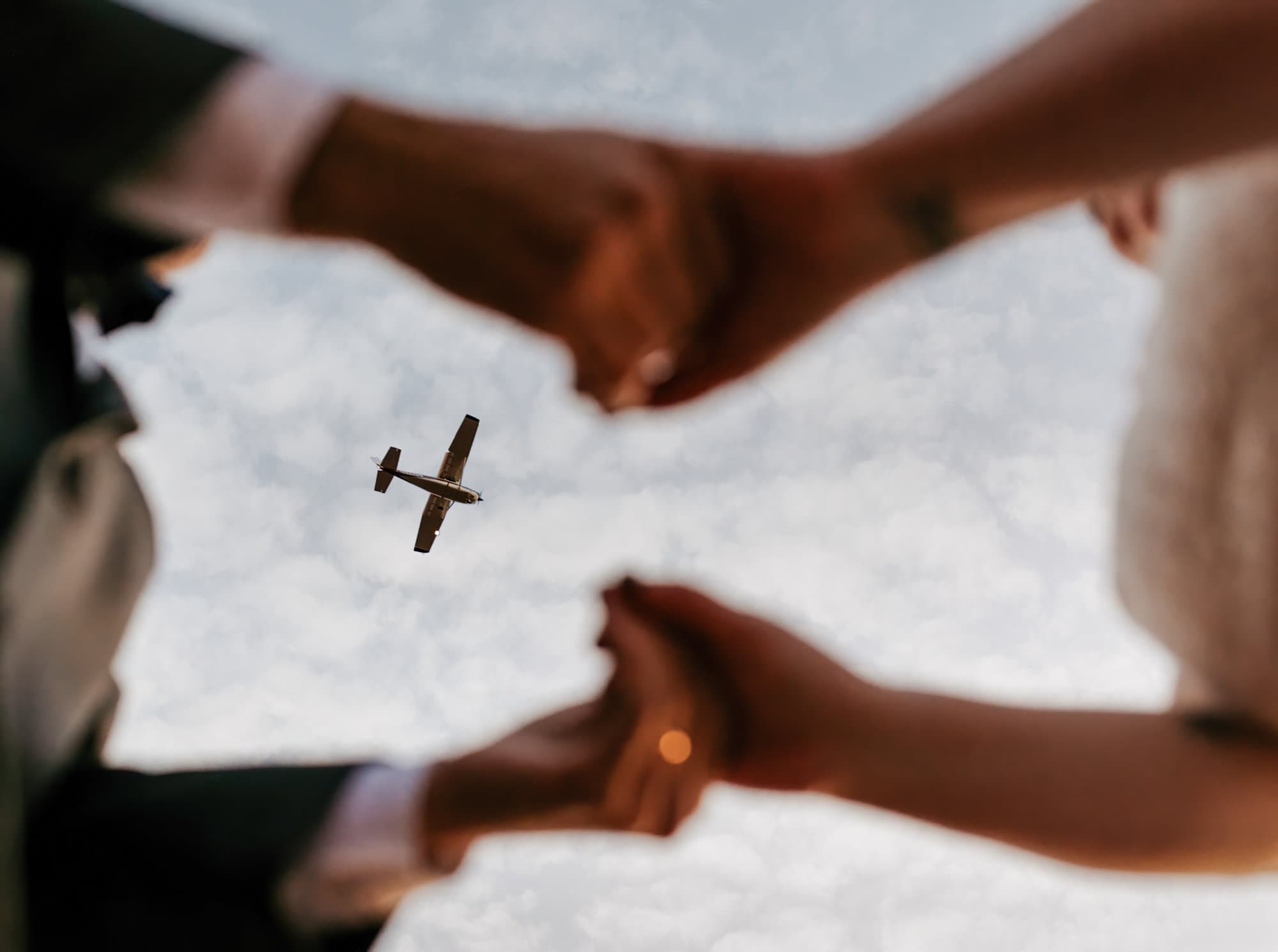 A plane flies over a couple as they hold hands.