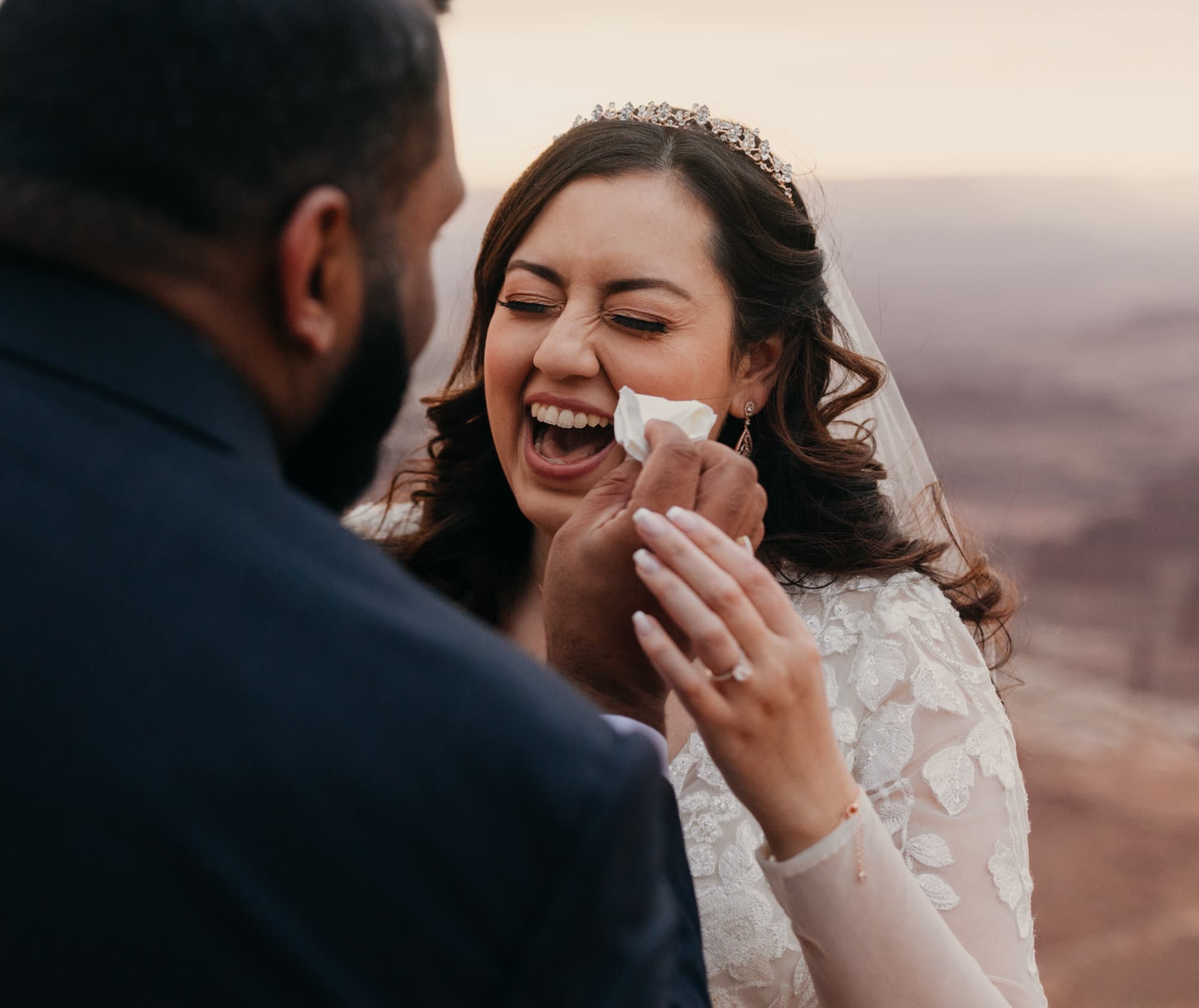 A groom wipes away the brides happy tears.