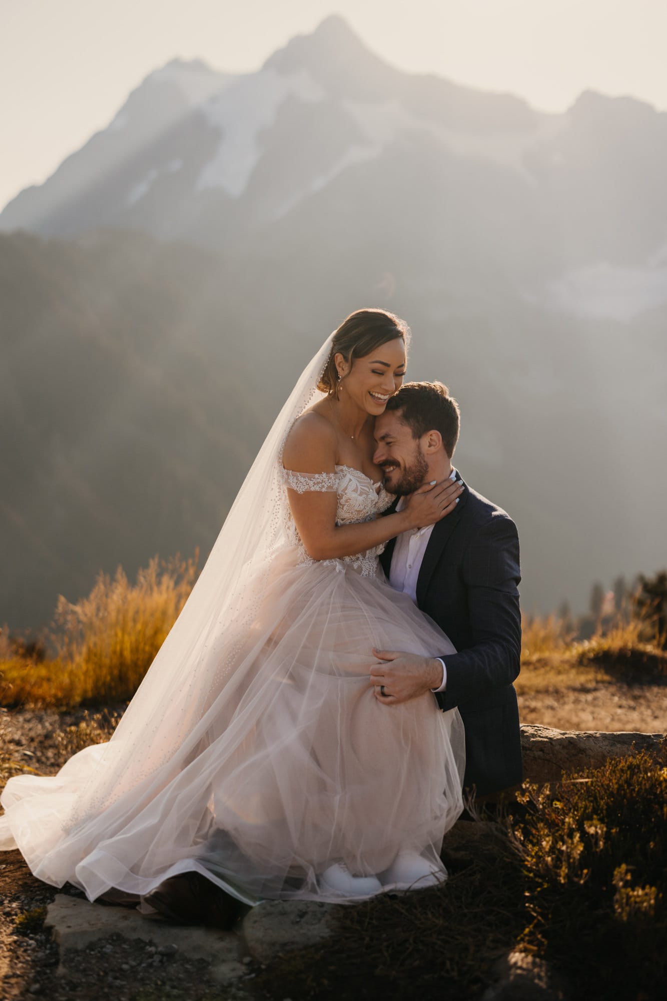 A couple cuddles up close together in the early morning light in the mountains.