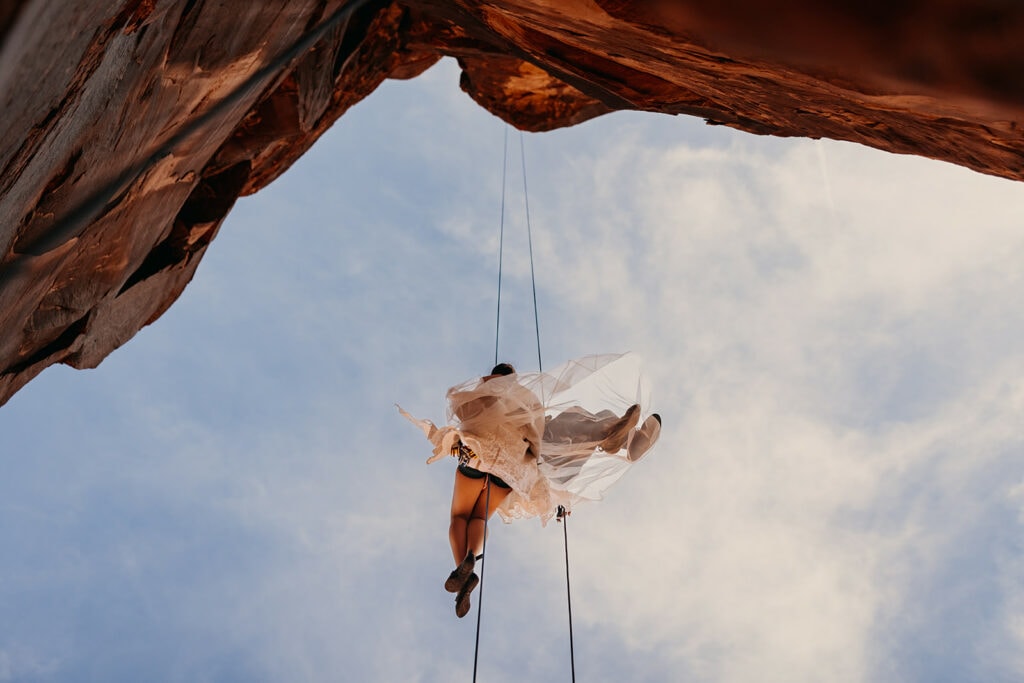 The dress sweeps over the grooms shoes during their rappel.