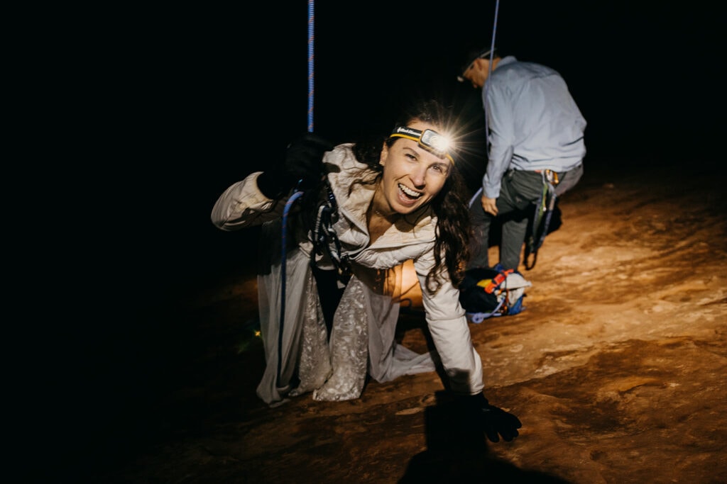 A bride smiles as she comes off of a hanging rappel.
