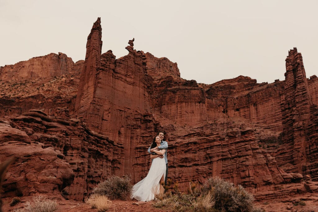 The groom holds the bride as they stand for a portrait.