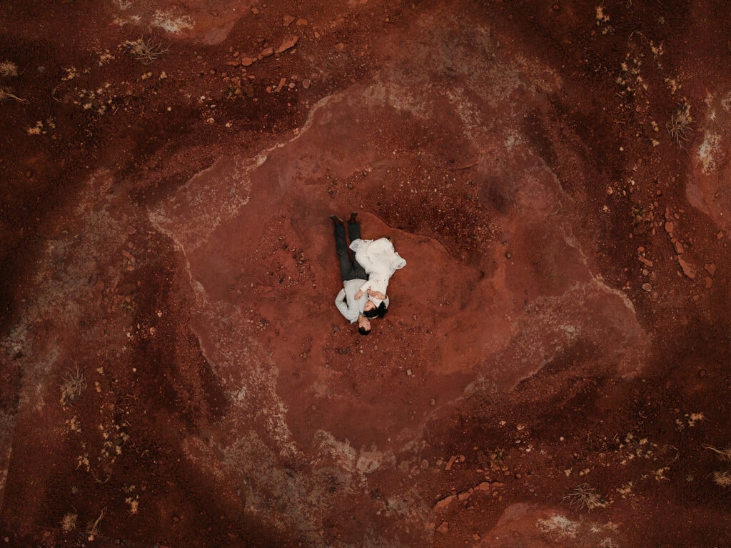 A couple cuddles on a rock during the evening.