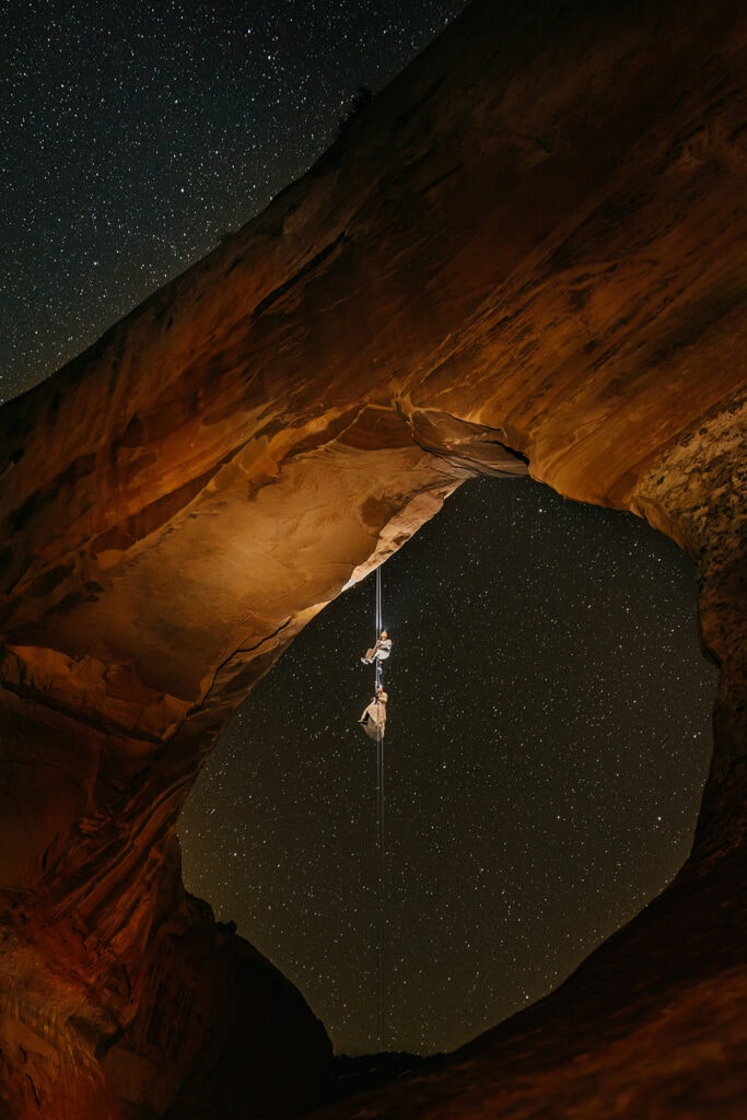 A couple is on a hanging rappel as they star gaze on their elopement day.