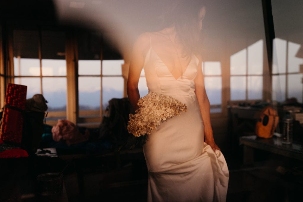 A detail photo of the bride's dress and flowers as she stands in the fire tower.