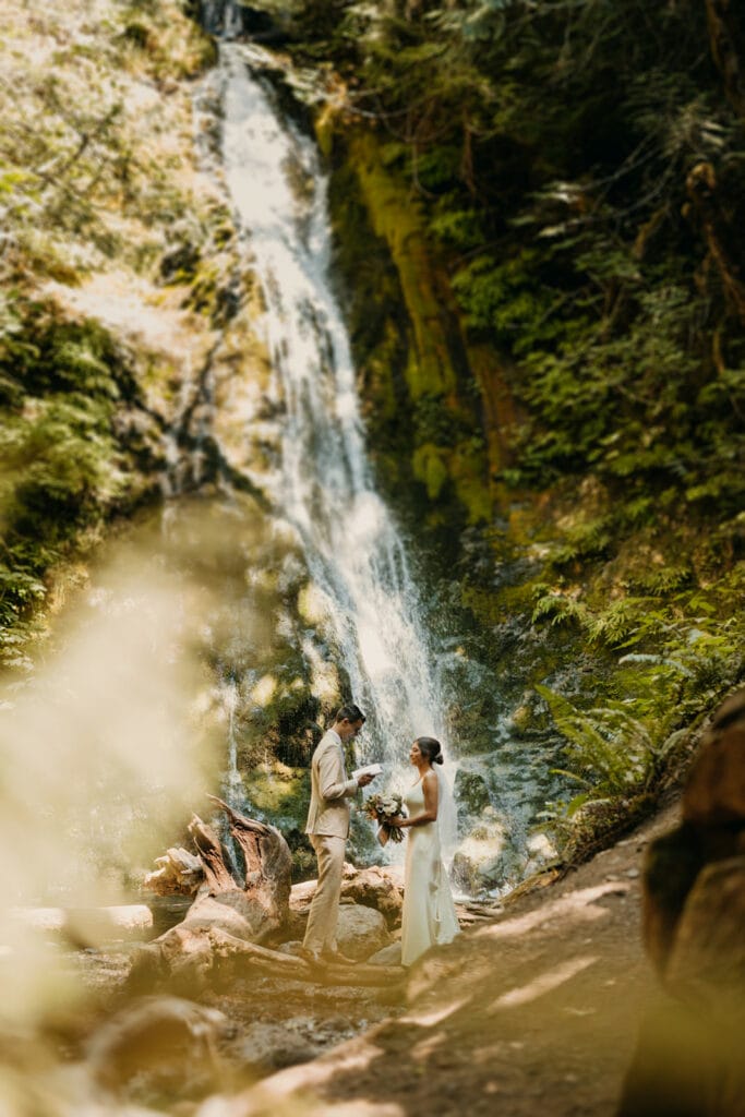 The bride and groom share their private vows with each other by a water fall.
