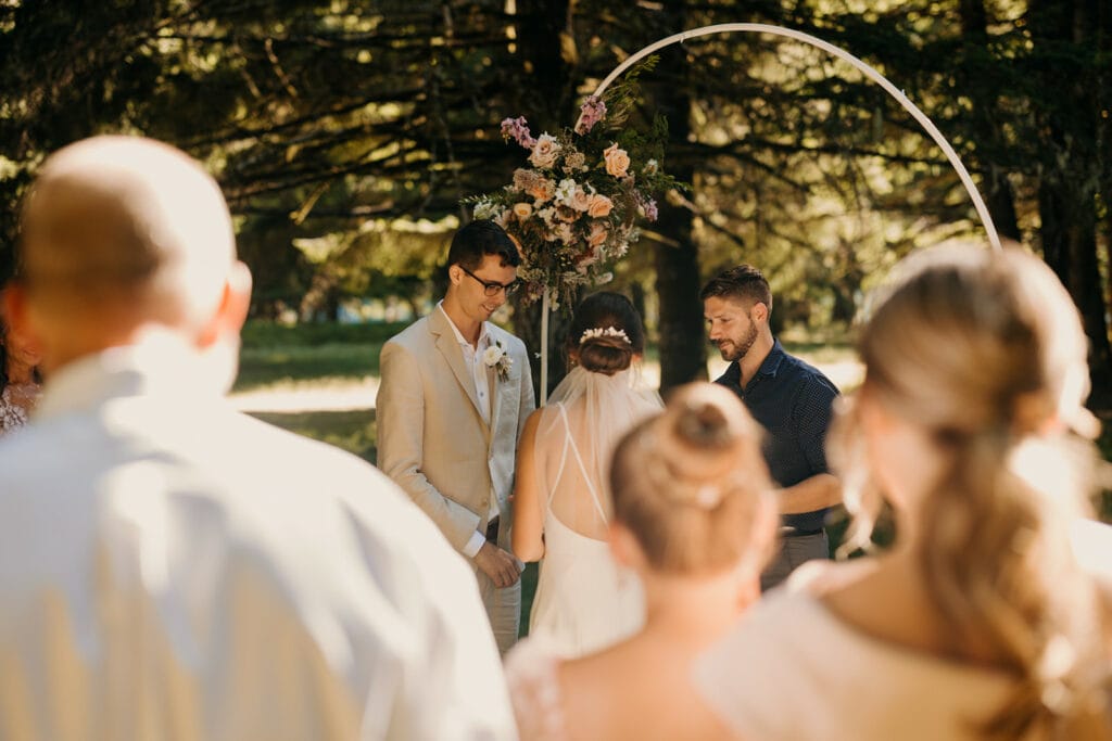 The groom smiles at the bride during their wedding ceremony.