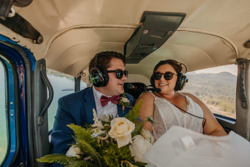 A couple smiles at each other while on a sea plane ride.