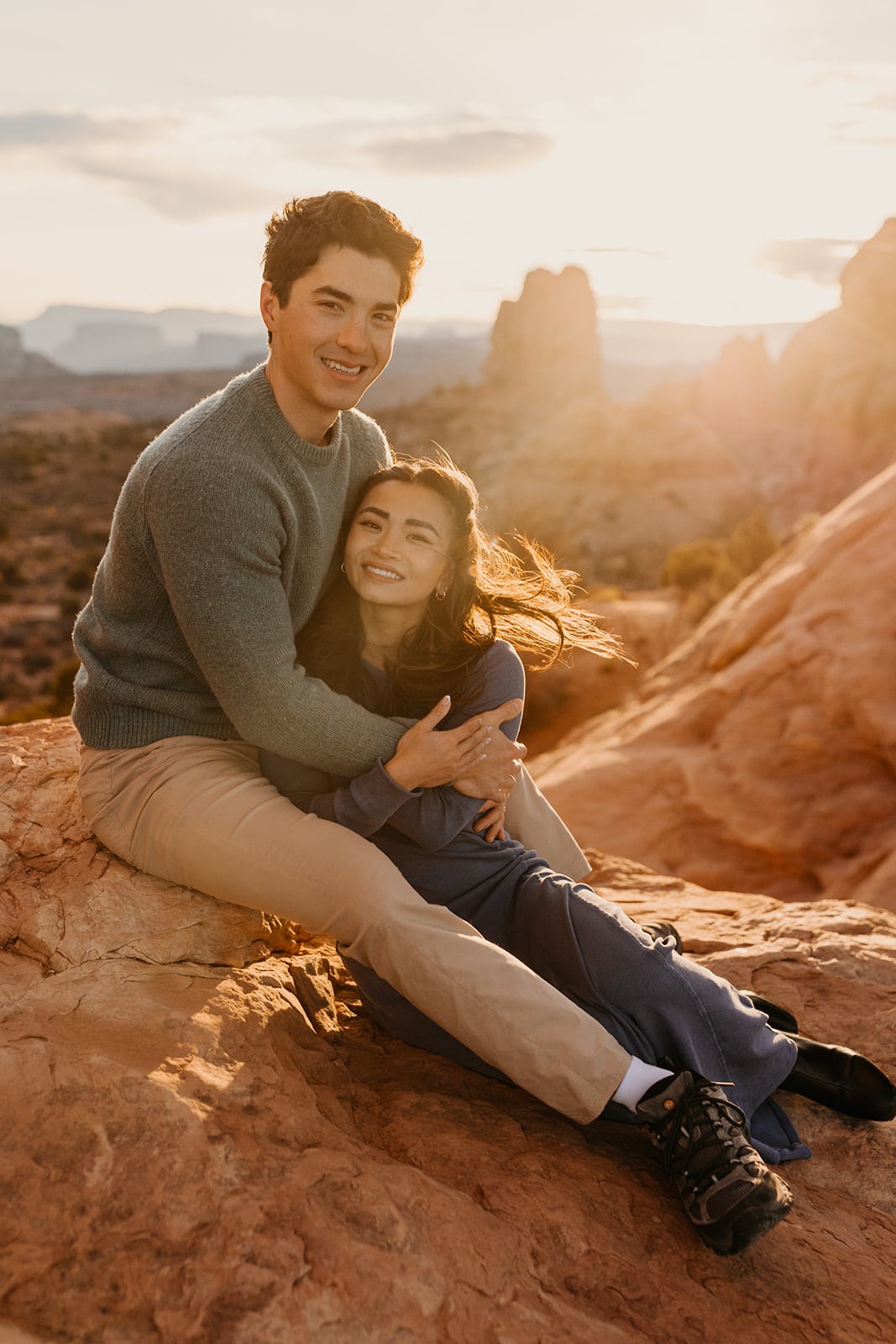 A man and woman sit together within Arches National Park during sunrise