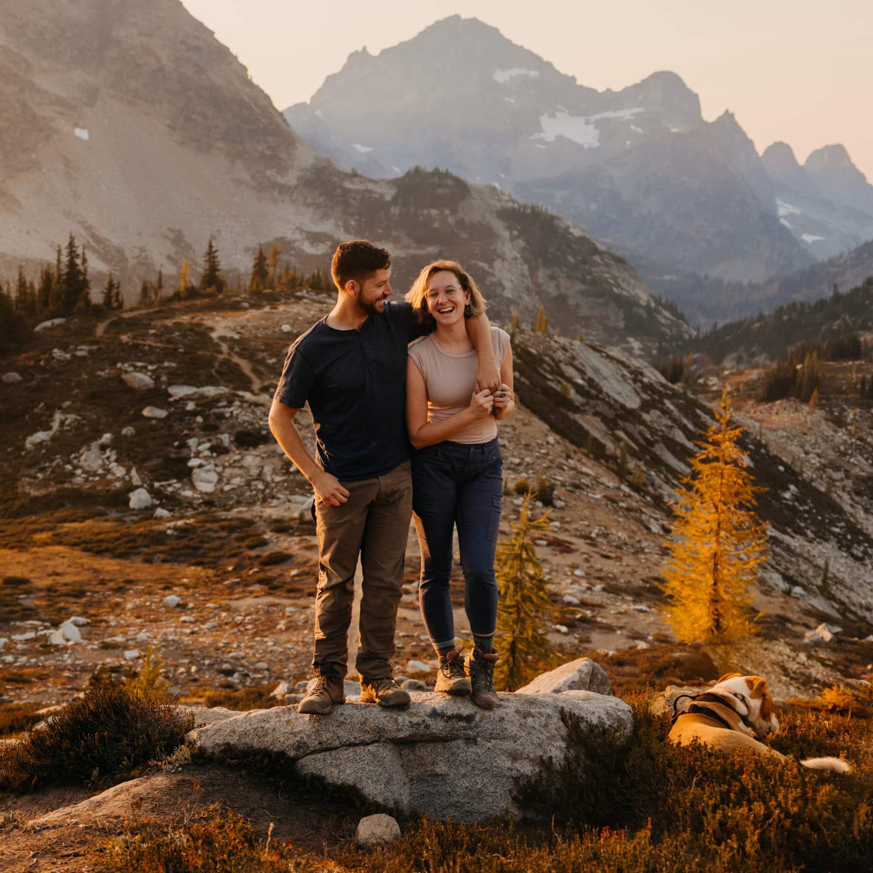 A couple smiles for a portrait in the mountains.