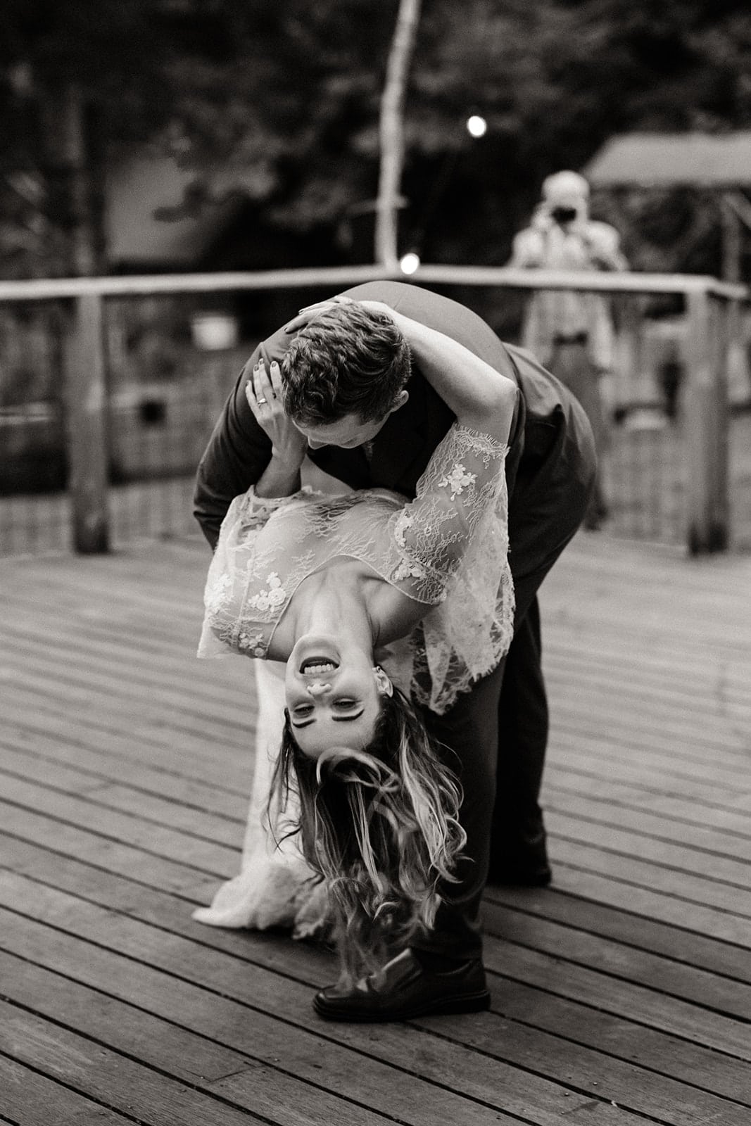 The groom dips the bride as they dance together.
