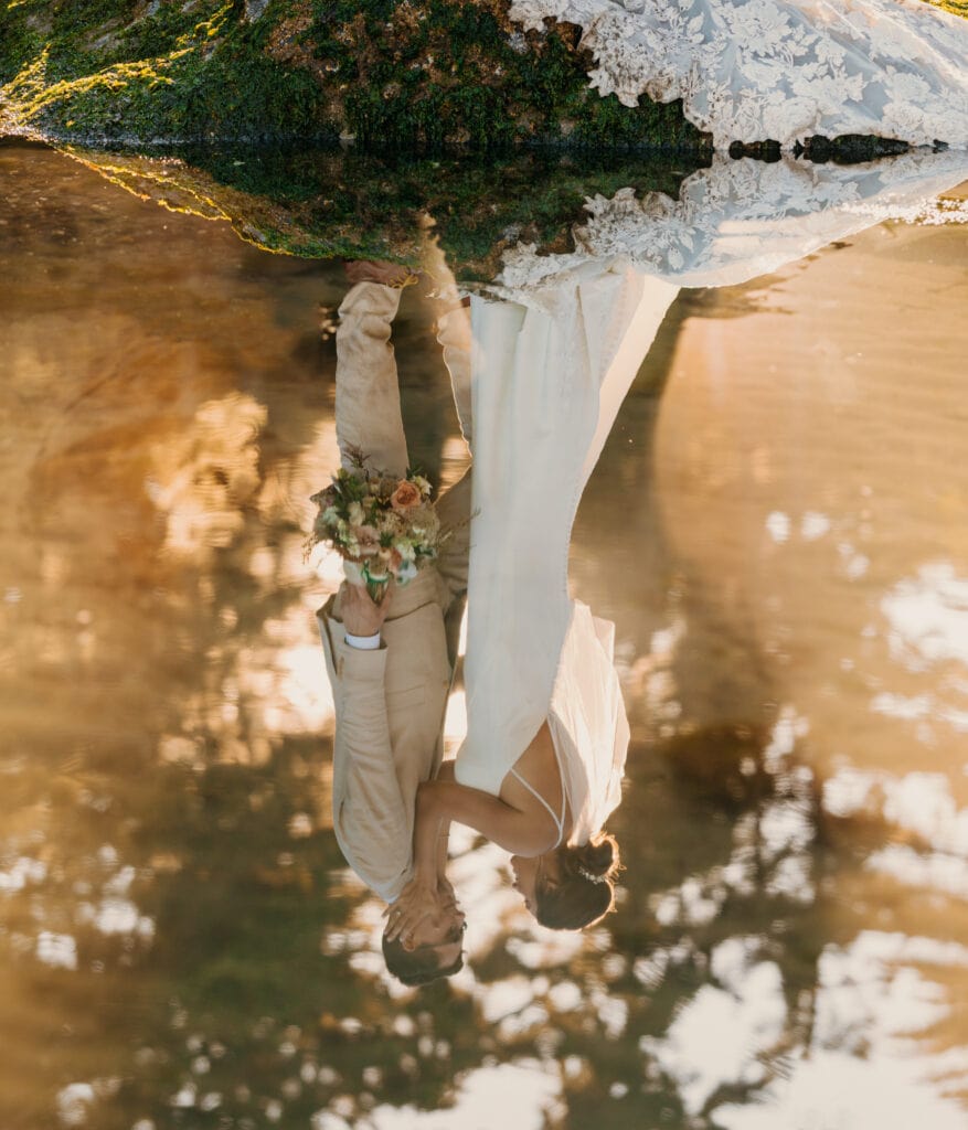 The couple stands together as their perfect reflection is below them.