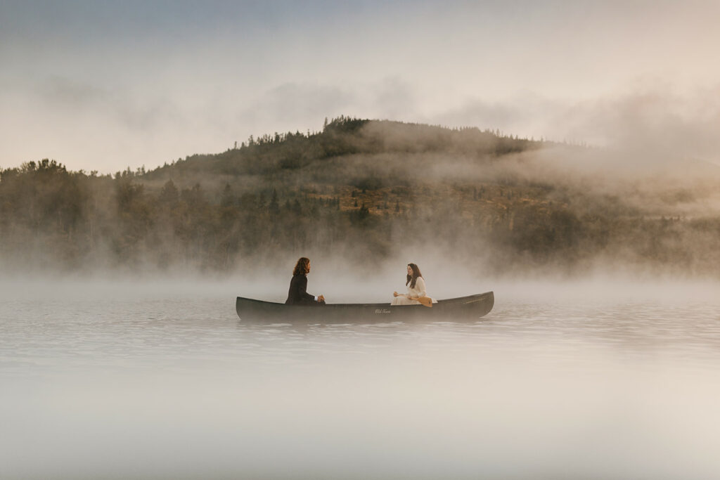 A couple canoes on a lake on a foggy morning.