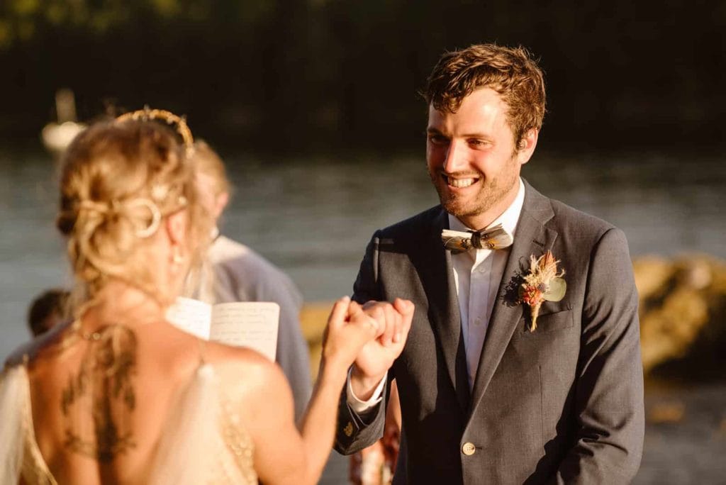 The bride and groom sharing a pinky promise while the groom smiles at his bride