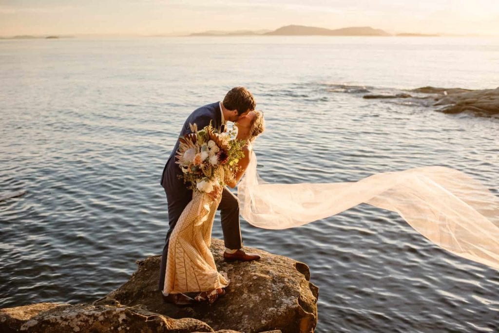 A couple shares an intimate kiss in the sunset light.