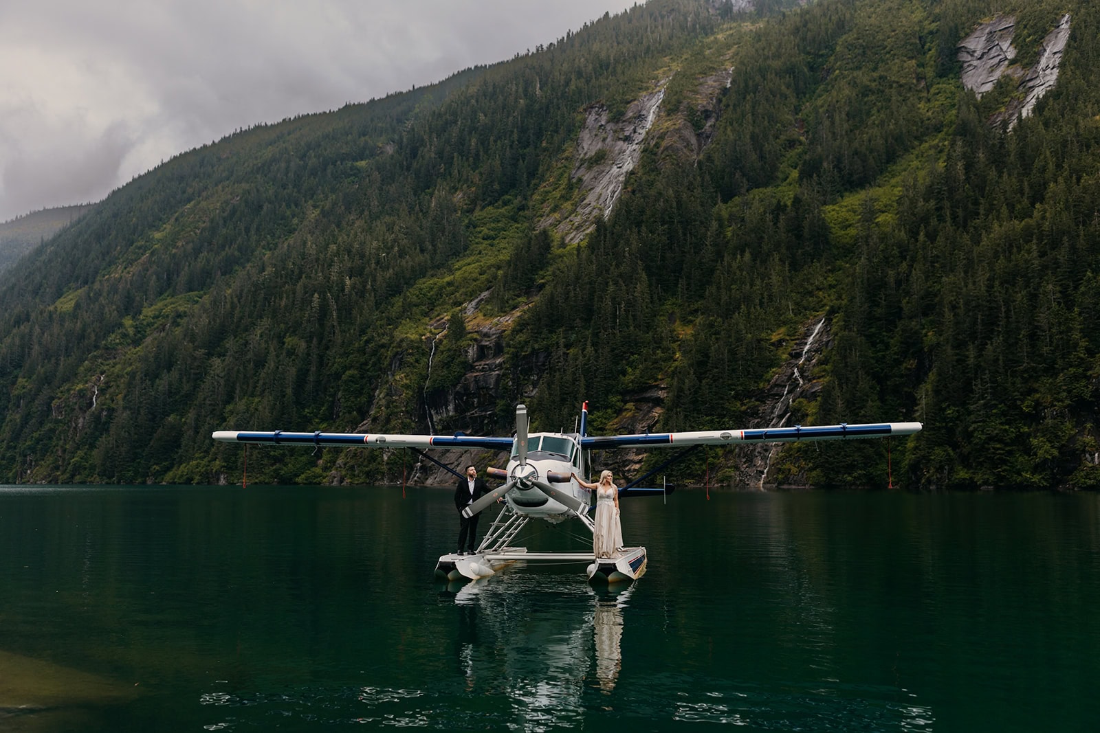 A couple stands on a seaplane in the bay off the coast of Juneau, Alaska.