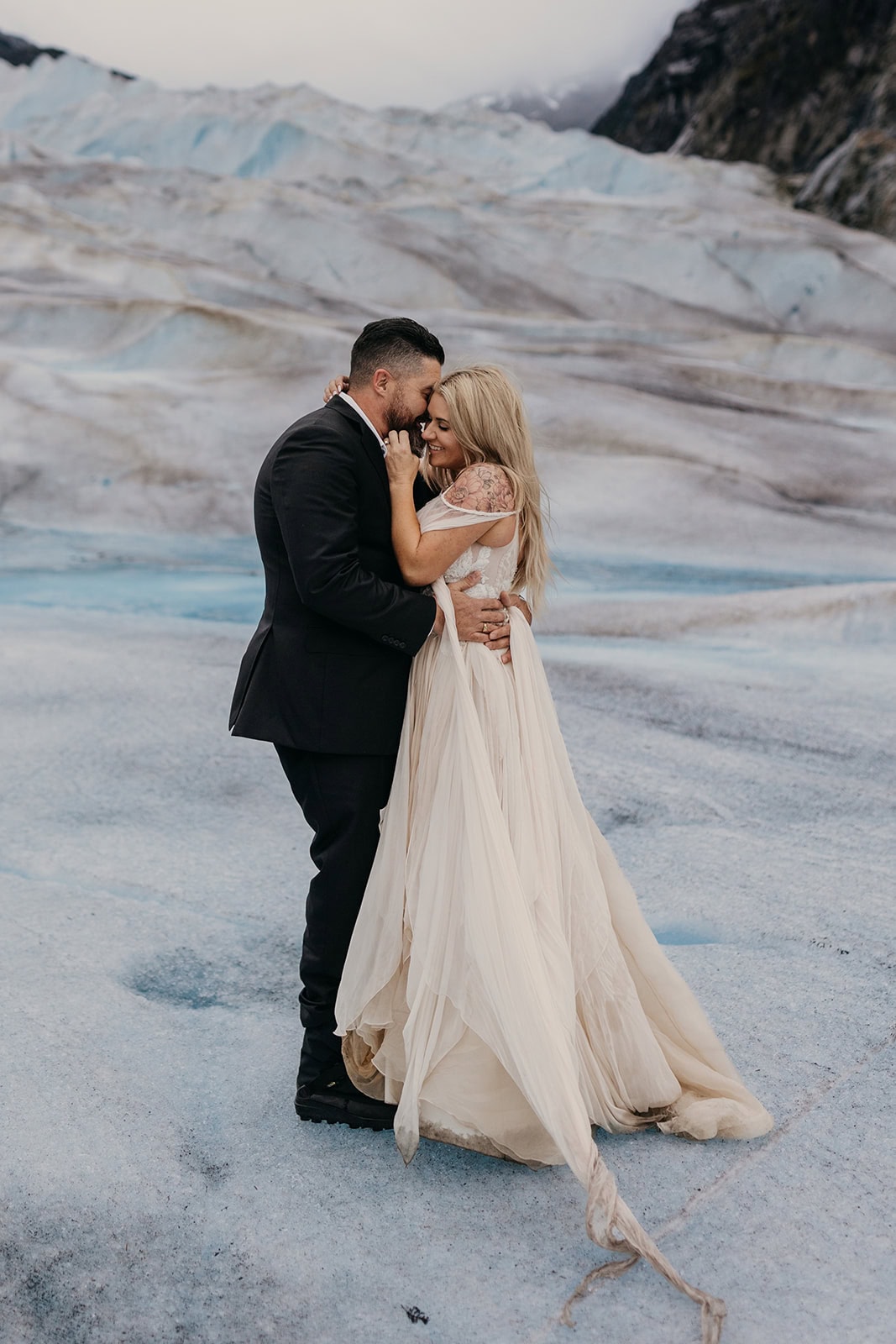 A couple holds each other closely standing on a glacier in Juneau.