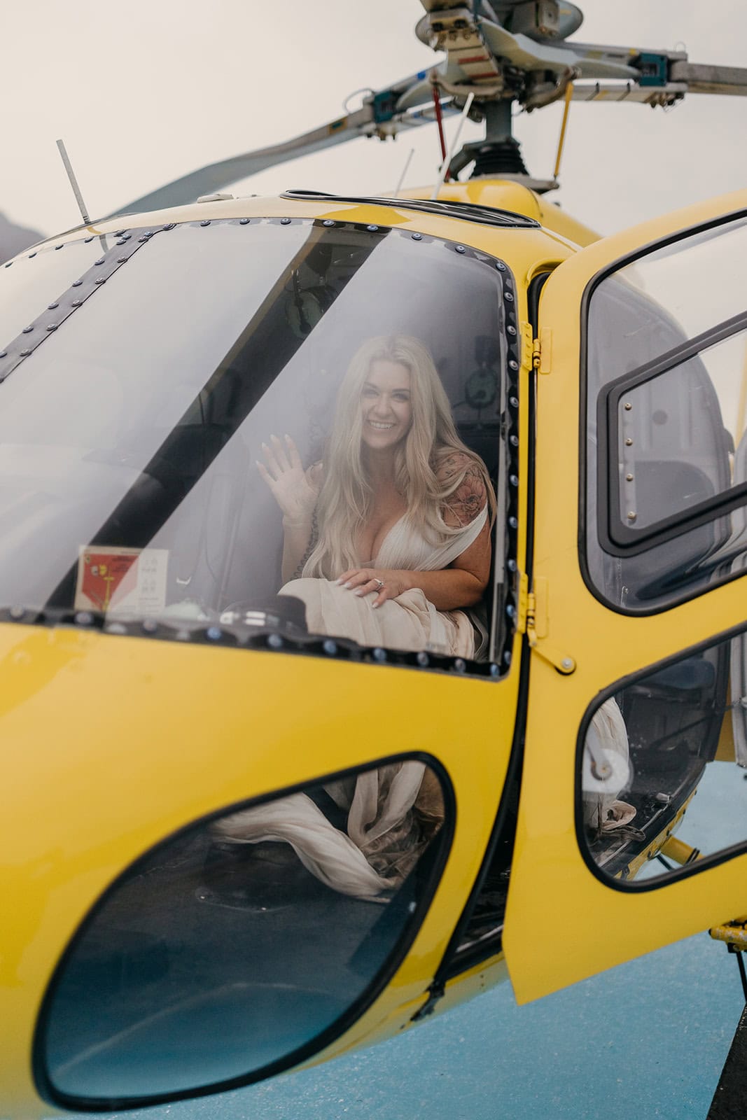 A bride waves hello to a camera while sitting in one of Coastal Air's helicopters.