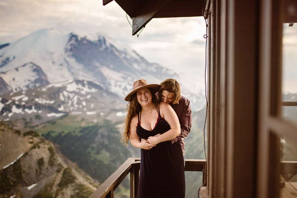 An engaged couple hold each other close on fremont tower in mt rainier.