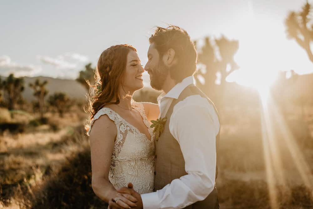 A couple stares into each other eyes as they share a slow dance as the sun goes down behind them.