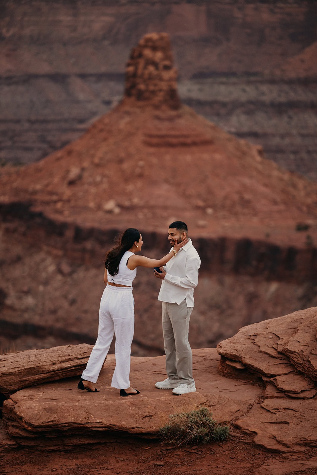 A girl wipes a tear from her partner's eyes after he finishes proposing.