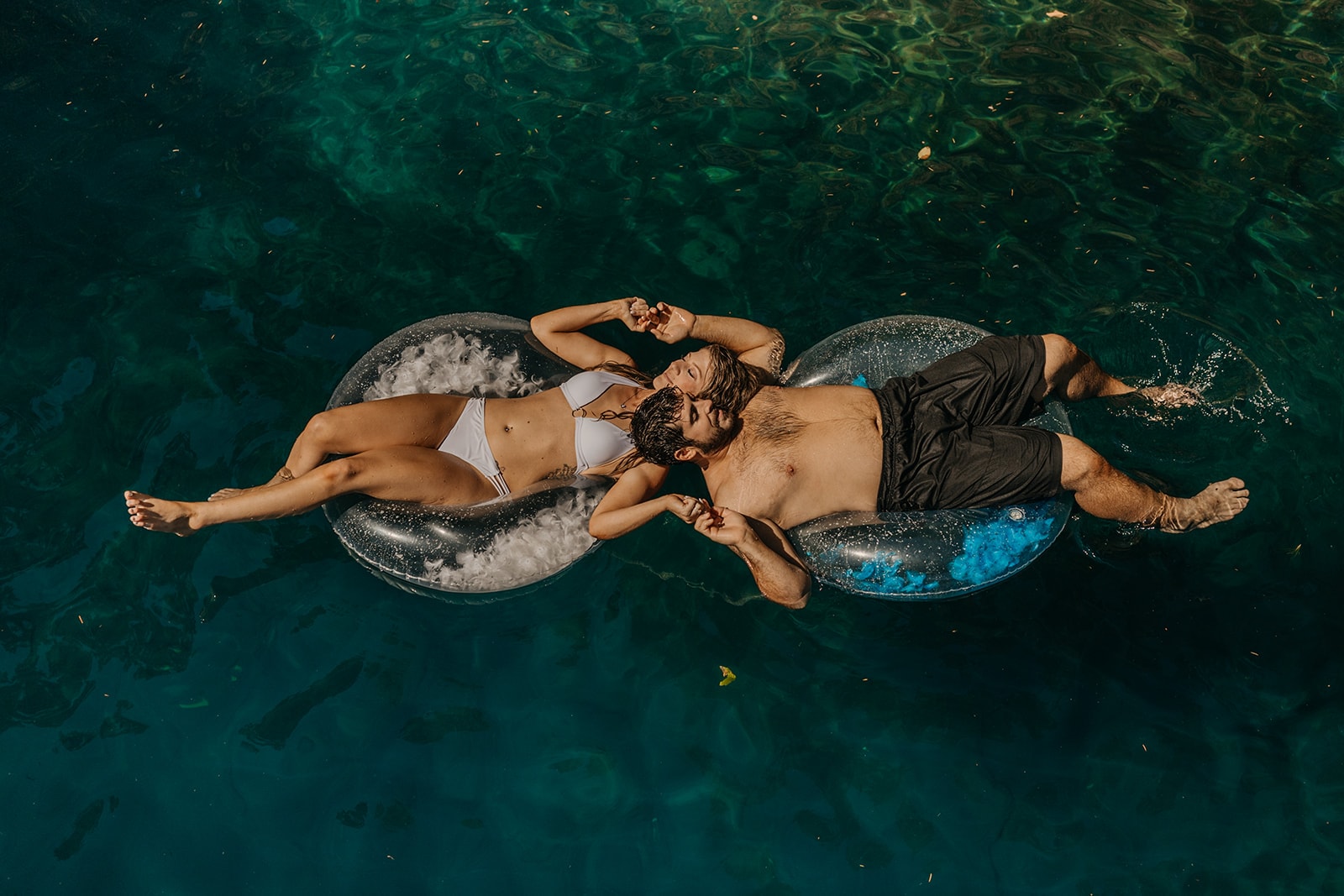 A couple holds hands while floating on the lake. 