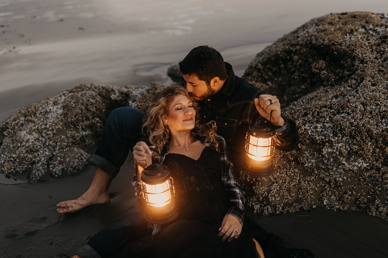 A couple cuddles up on a rock on the coast.