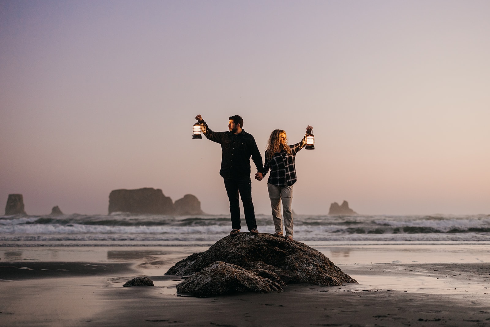 A couple holds lanterns as the sky grows darker. 