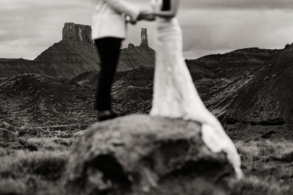 A detail photo of Castleton in the background as the couple holds hands.