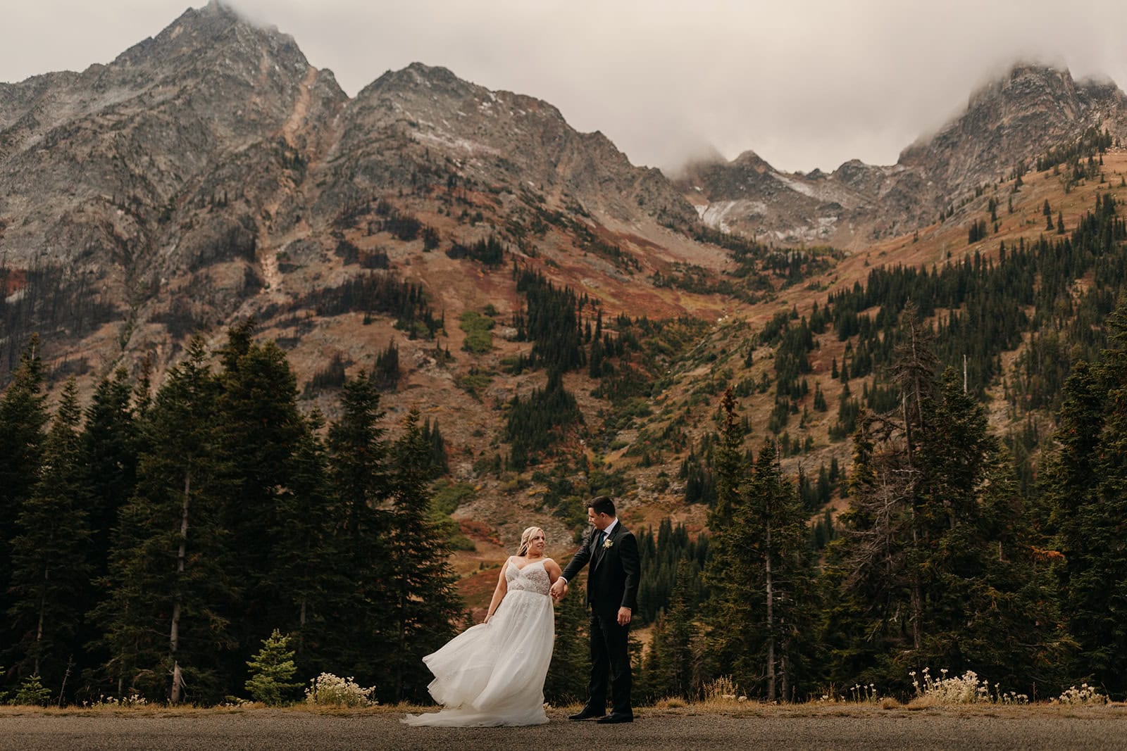 A couple lovingly stares at each other holding hands on a fall day in the mountains.