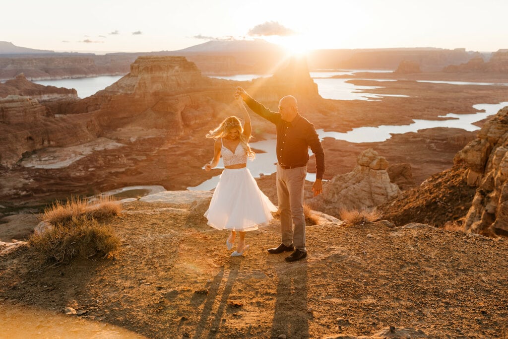 A groom spins his bride in the sunlight.