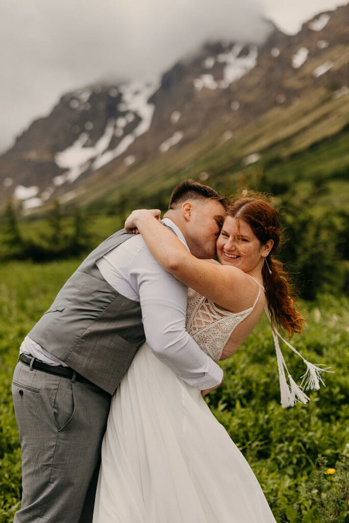 The bride smiles at the camera as the wind catches her dress.