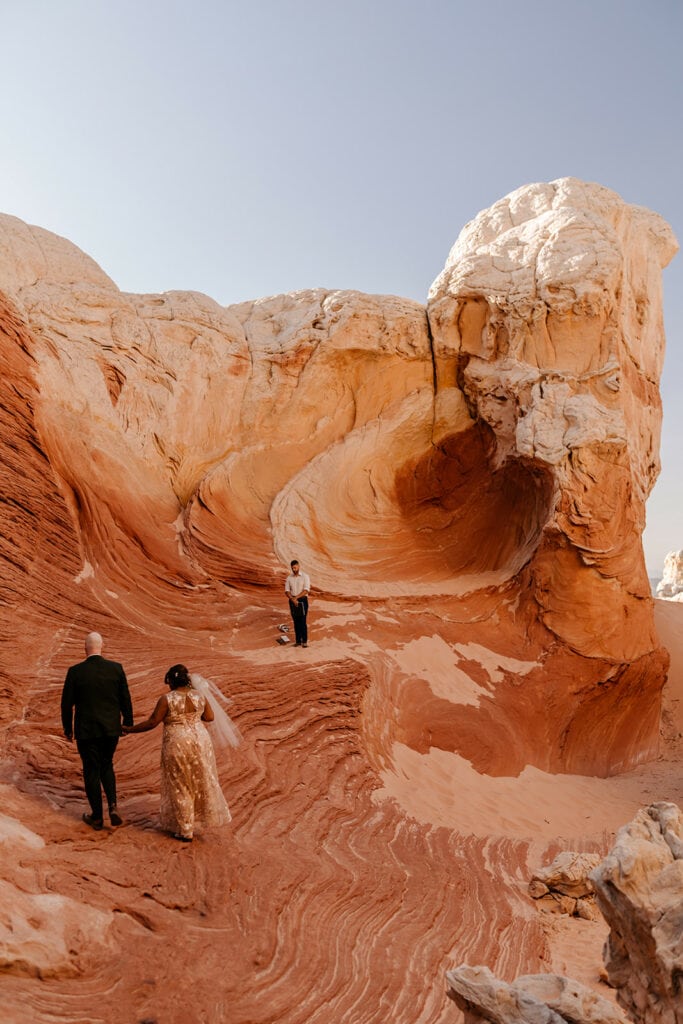 A couple walks hand in hand together towards their wedding ceremony.
