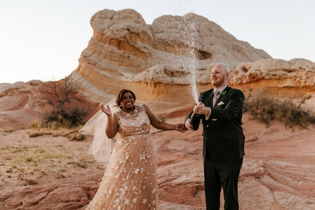 A couple sprays champagne in celebration of getting married.