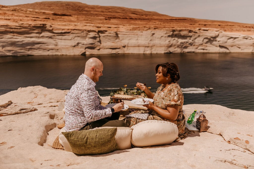 A couple shares cake together as a boat passes by below them.