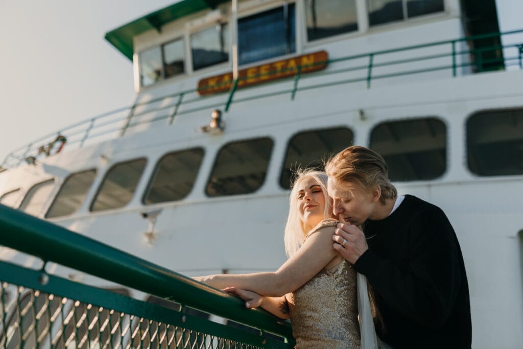 A groom kisses the shoulder of teh bride while on the ferry.