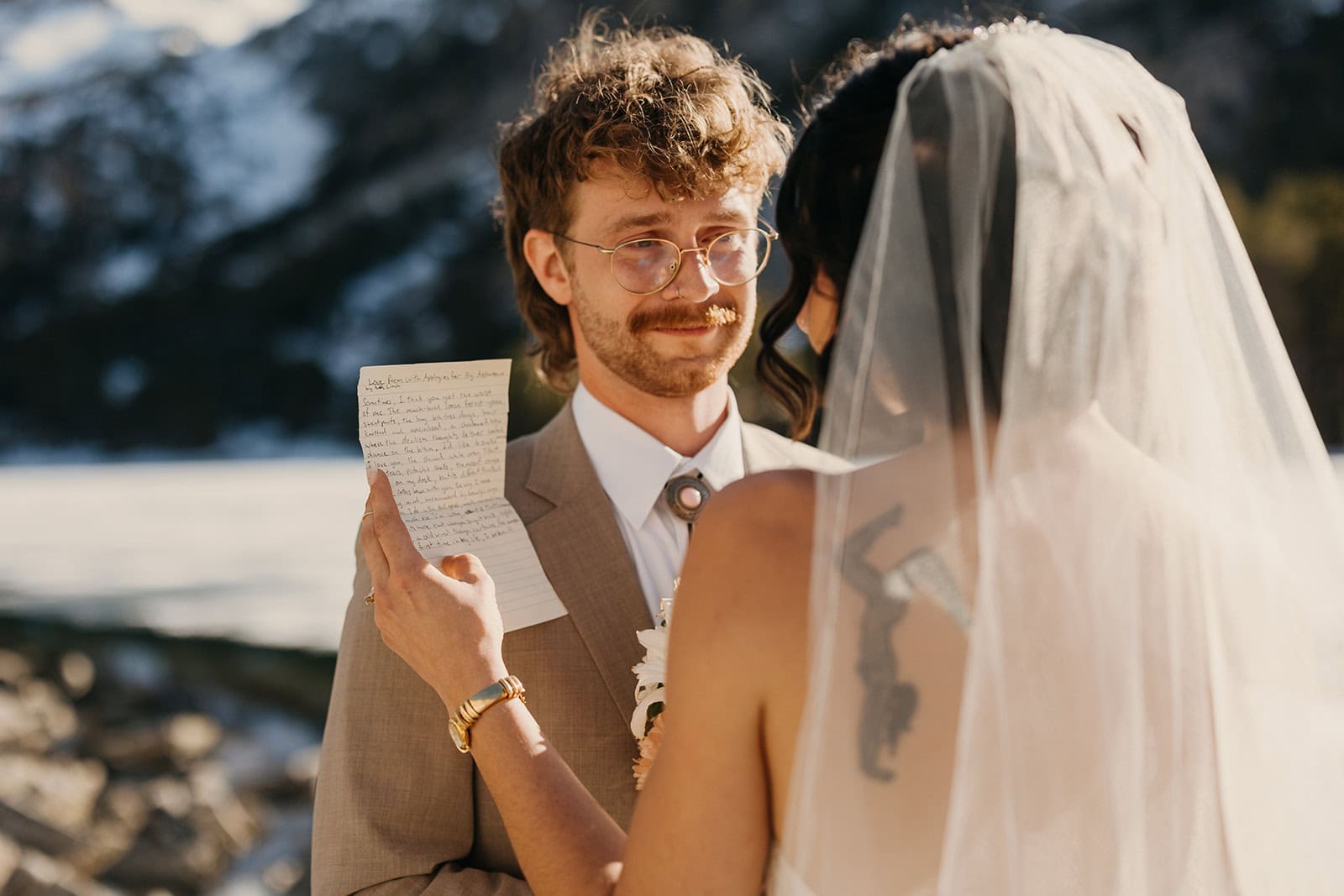 A groom listens intentionally and emotionally as his bride reads her vows.