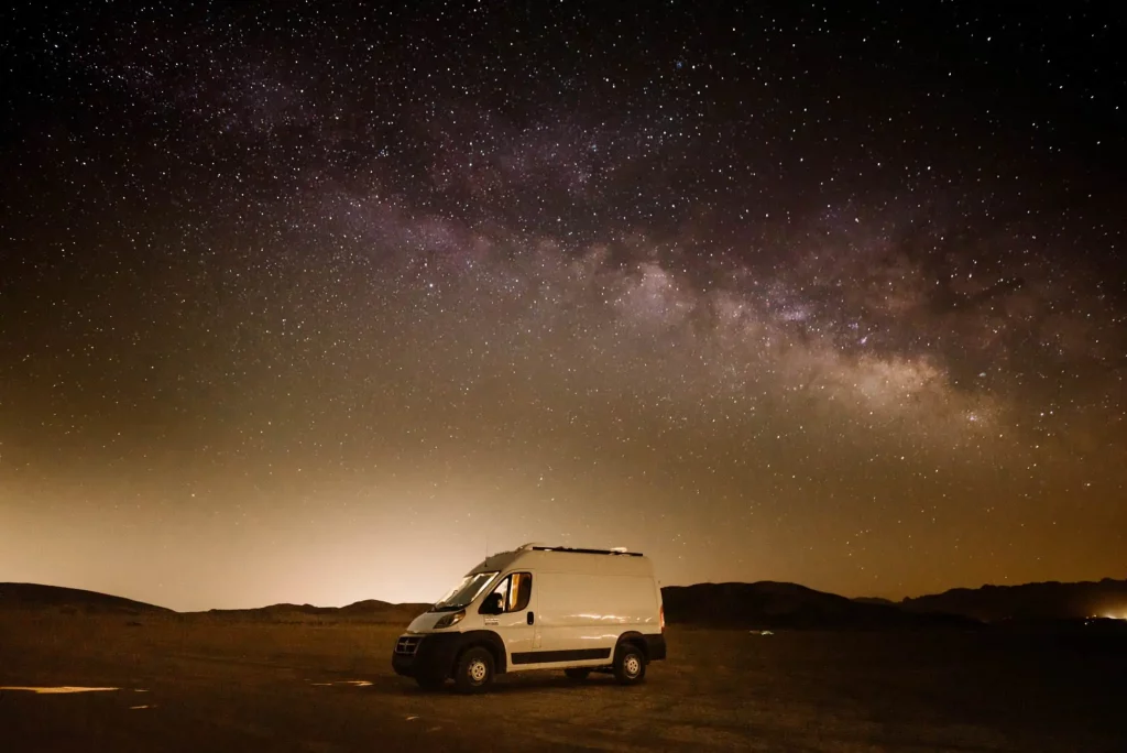 A van at camp under the milky way.
